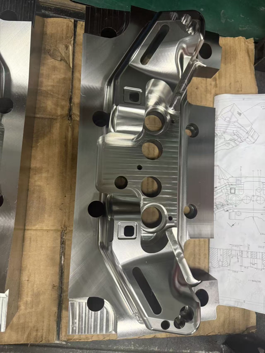 Precision mold cavity component reviewed beside its controlled engineering drawing